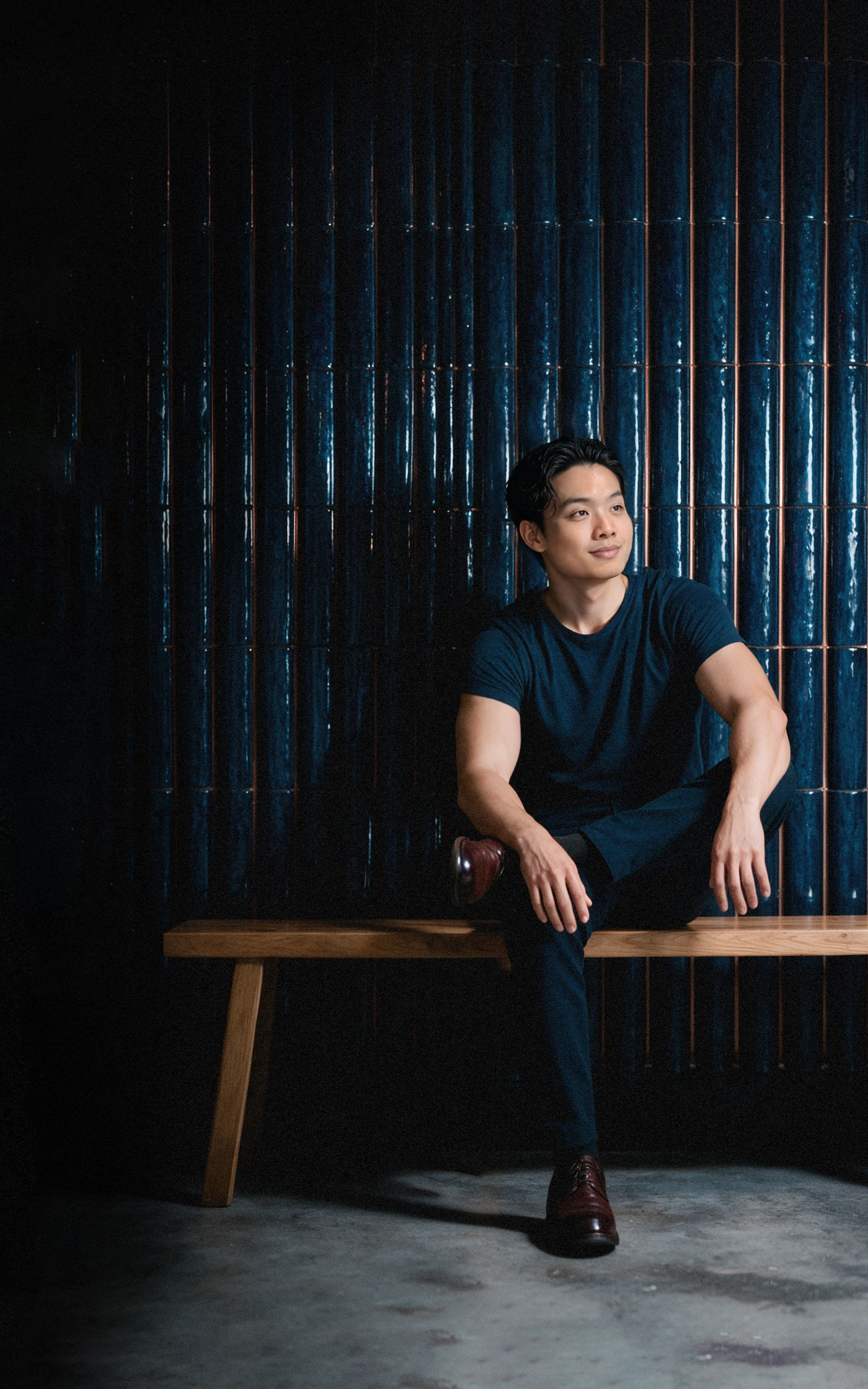 Ren Yang Tan seated on a timber bench in front of a slatted oak screen